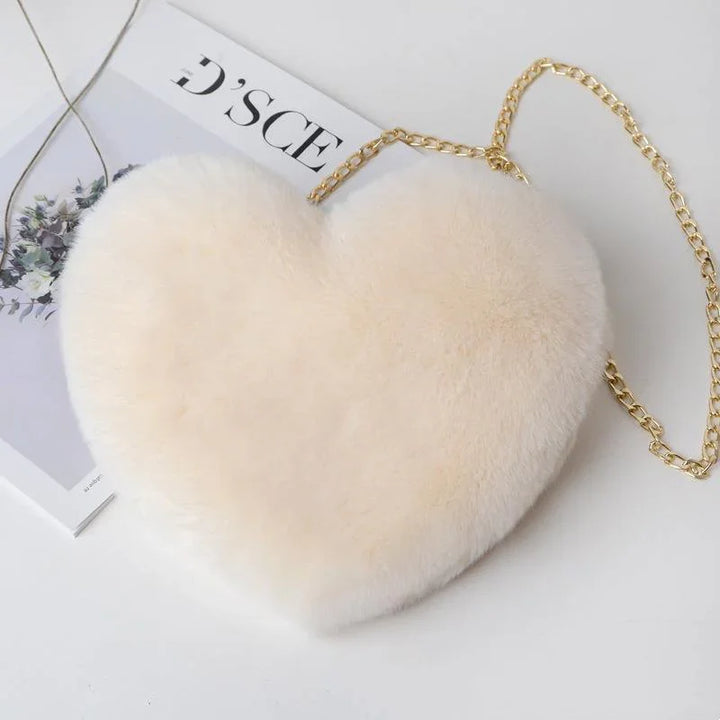 Soft cream heart-shaped plush handbag with gold chain strap on magazine