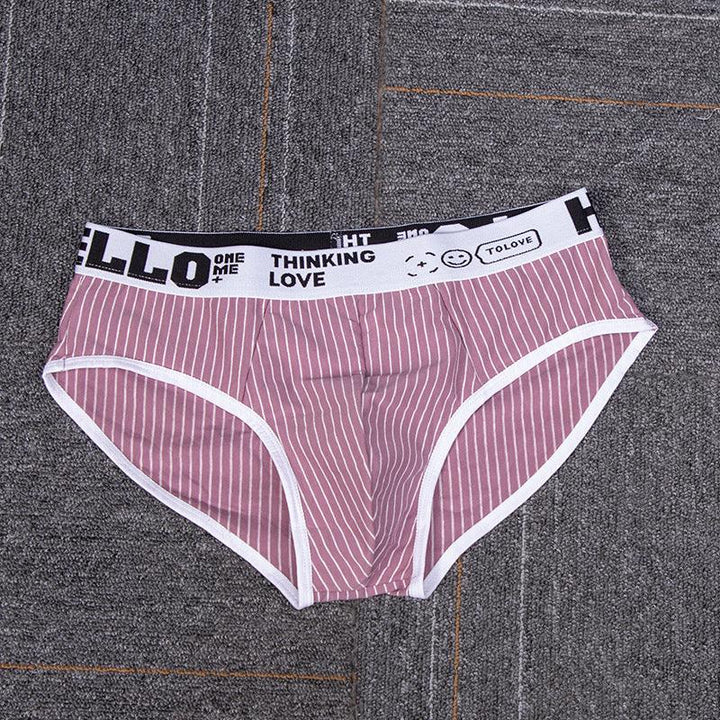 Pink striped men's briefs with white waistband featuring black text and smiley face on gray carpet