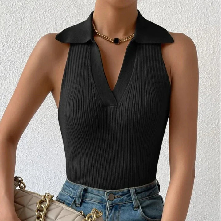 Woman wearing black ribbed sleeveless top with collar, gold chain necklace, and blue denim jeans