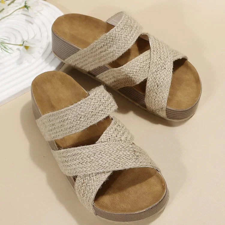 Beige woven sandals with crisscross straps and cushioned footbed on neutral background