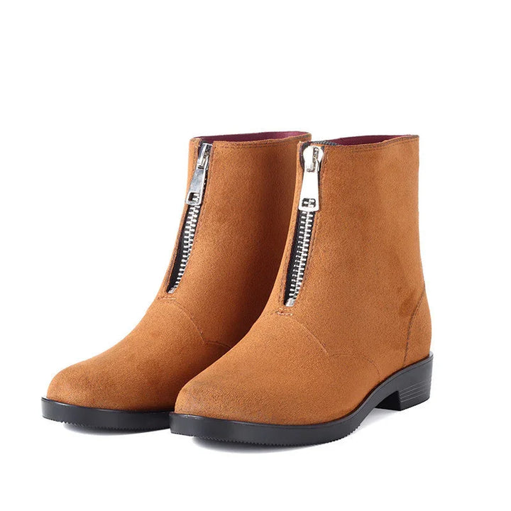 Brown suede ankle boots with front silver zipper and black low heel on white background