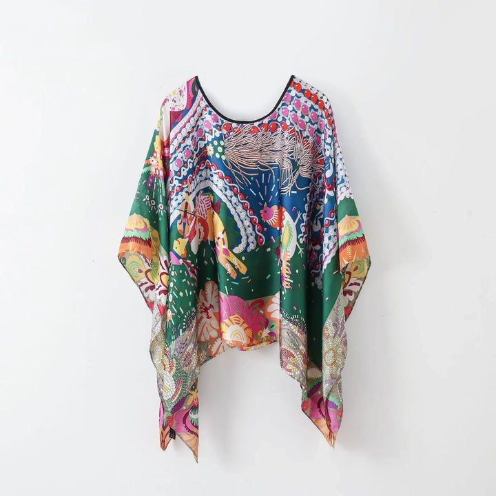 Colorful bohemian kimono with floral and abstract patterns hanging on white wall