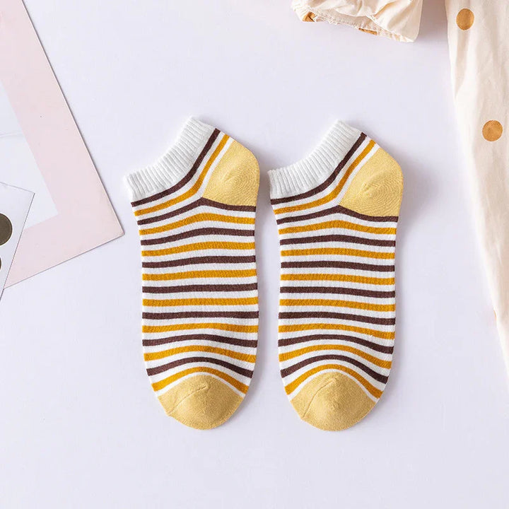 Pair of yellow, brown, and white striped ankle socks laid flat on white surface