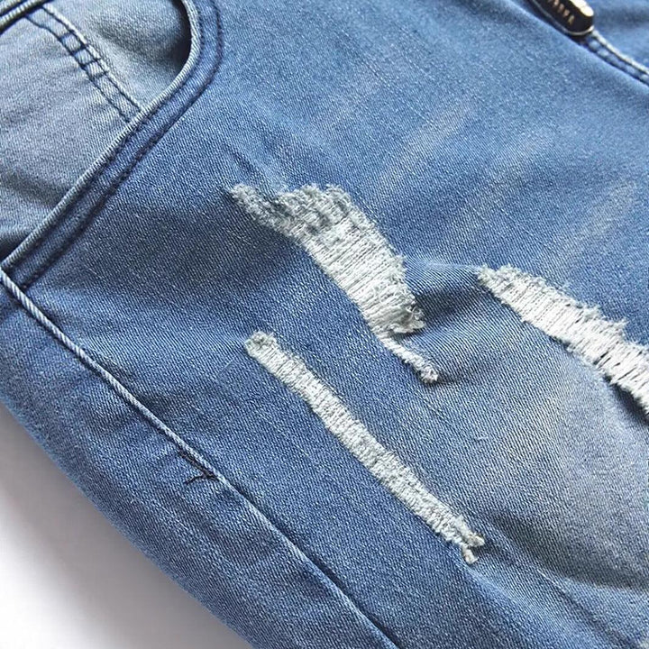 Close-up of light blue distressed denim jeans with visible frayed tears and stitching detail