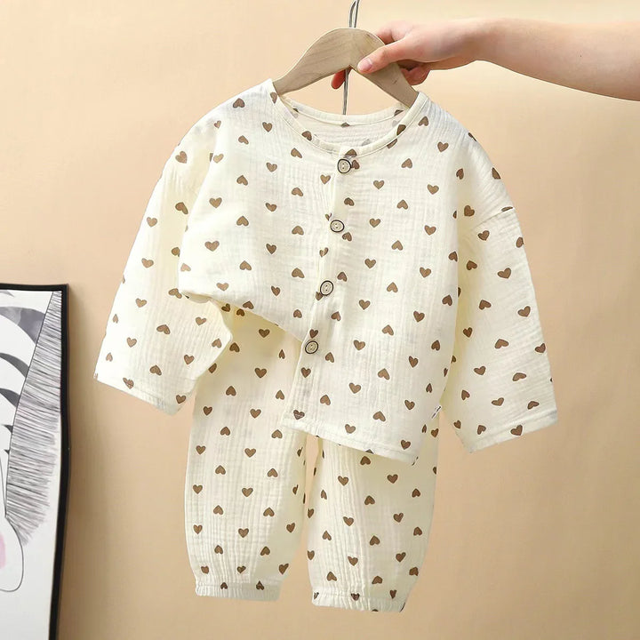 Cream-colored baby outfit with brown heart prints, buttoned long-sleeve top and matching pants