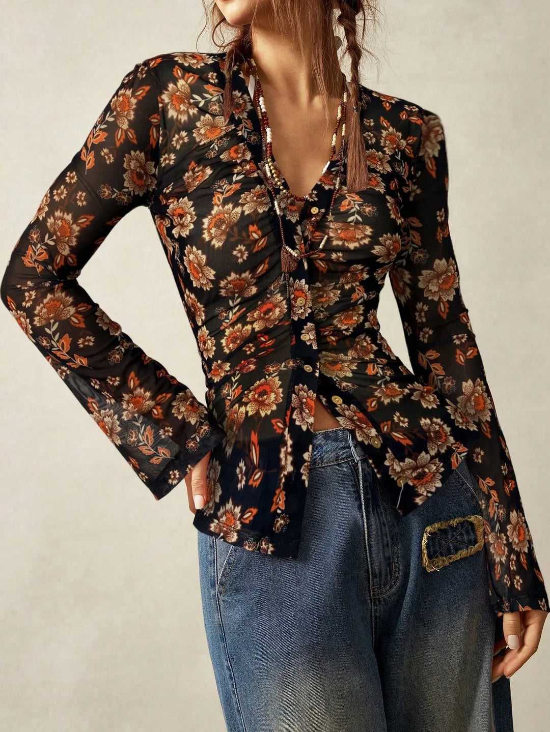 woman wearing a sheer black floral button-up blouse with long sleeves and blue jeans