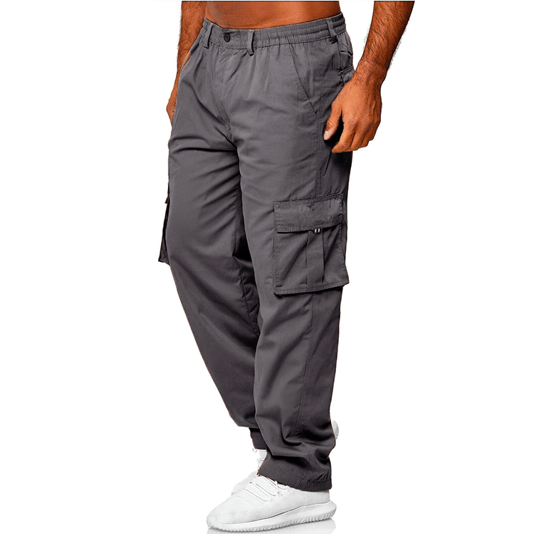 Men's gray cargo pants with multiple pockets worn with white sneakers on white background