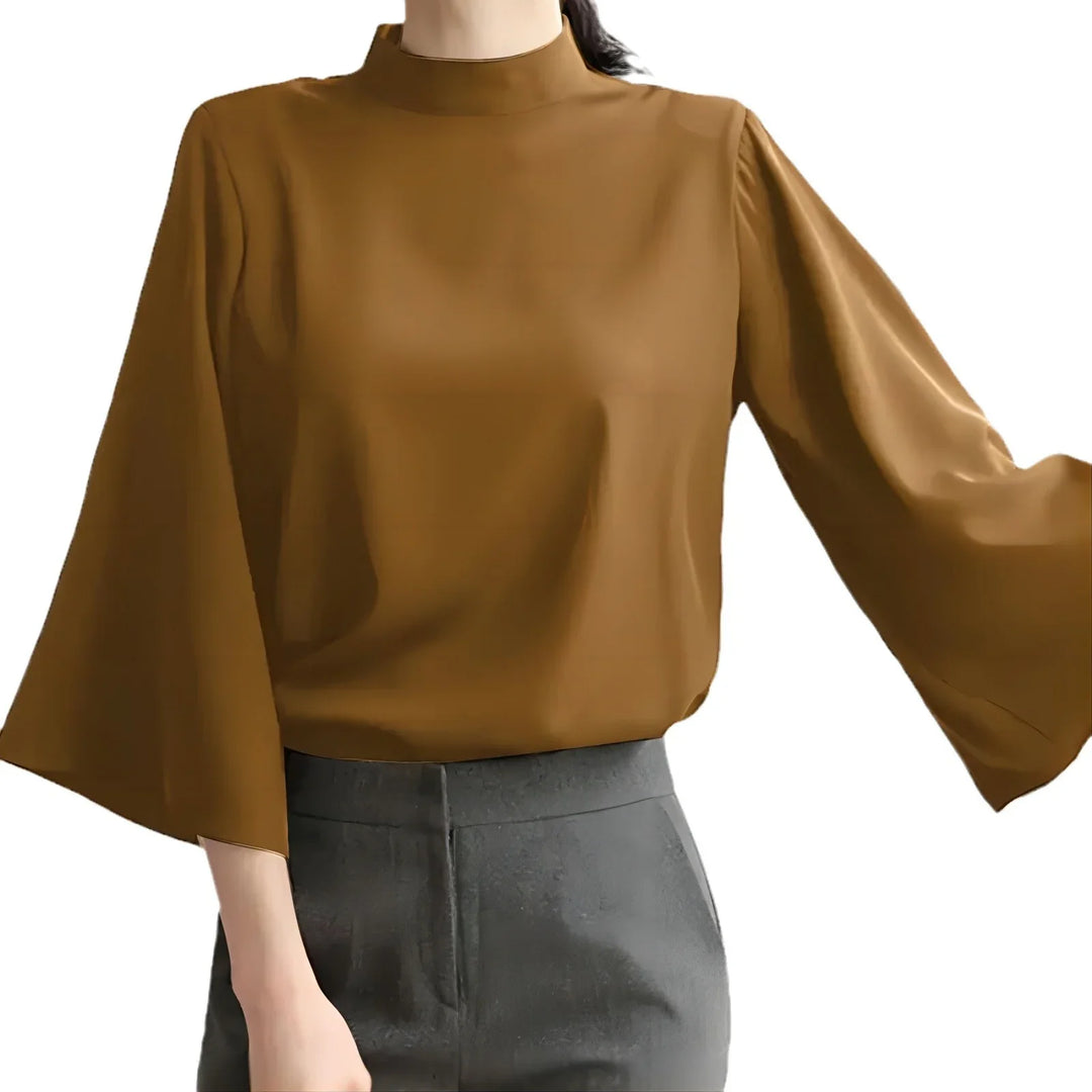 Woman wearing brown blouse with wide sleeves and high neckline, paired with grey pants