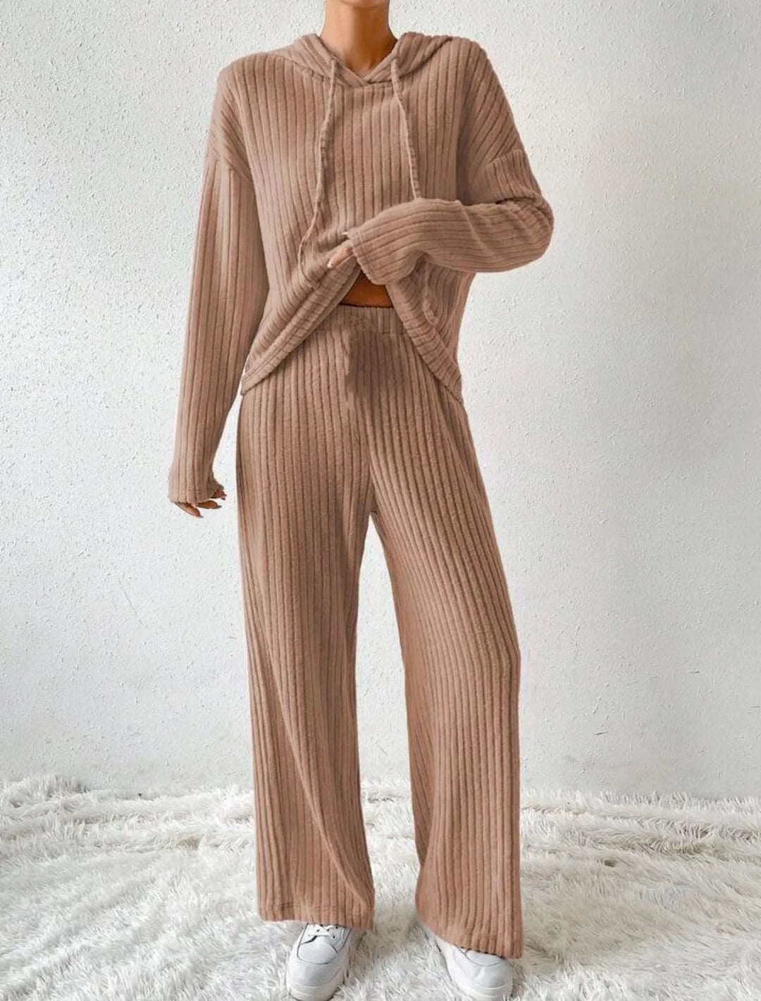 Woman wearing beige ribbed knit loungewear set with hooded top and wide-leg pants paired with white sneakers
