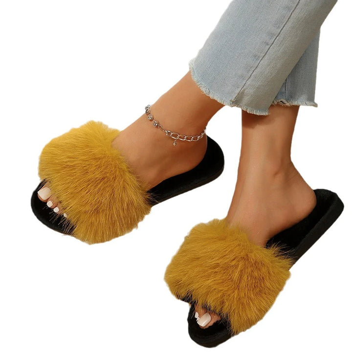 Feet wearing black slippers with mustard yellow fuzzy fur straps and cropped light blue jeans