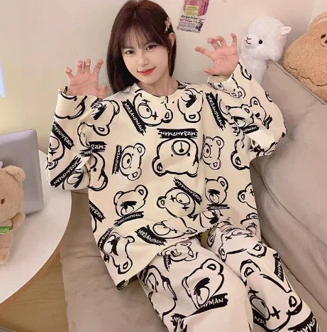 Young woman sitting on couch wearing beige oversized sweatpants and sweatshirt with black teddy bear prints