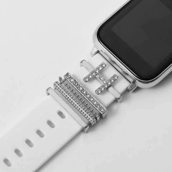 Silver rhinestone charms on a white smartwatch band with a black screen