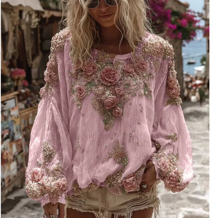 Woman wearing a pink floral embroidered blouse with puff sleeves and beige distressed shorts outdoors