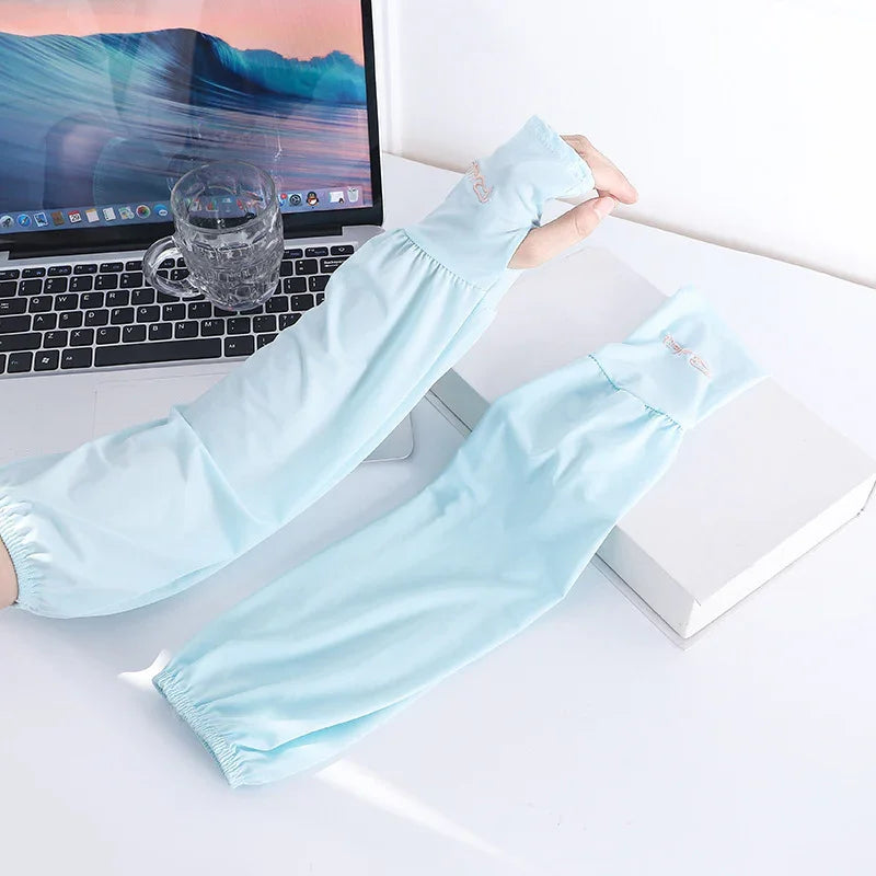 light blue sun protection arm sleeves next to laptop and glass cup on white desk