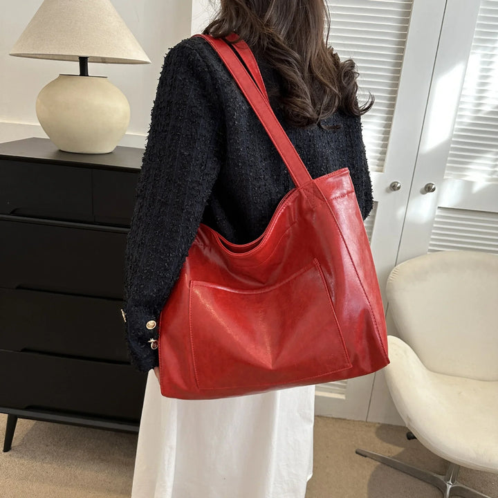 Woman wearing black sweater carrying large red leather shoulder bag indoors