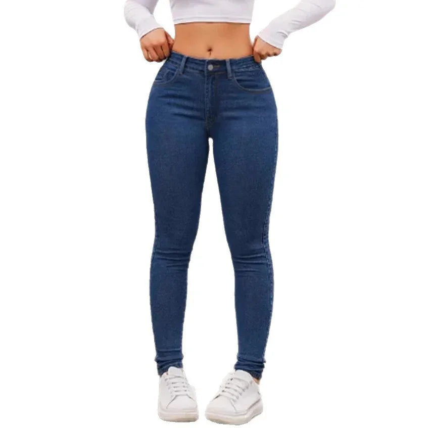 Woman wearing high-waisted dark blue skinny jeans with white sneakers and white crop top