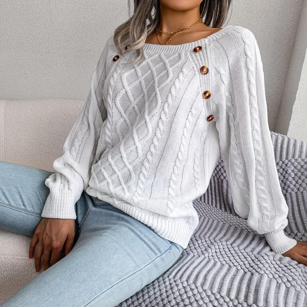woman wearing white cable knit sweater with brown buttons and light blue jeans sitting on textured gray blanket