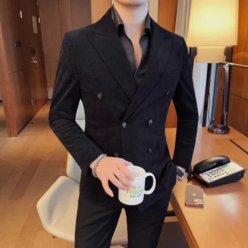 Man wearing black double-breasted blazer and shirt holding white coffee mug in modern office