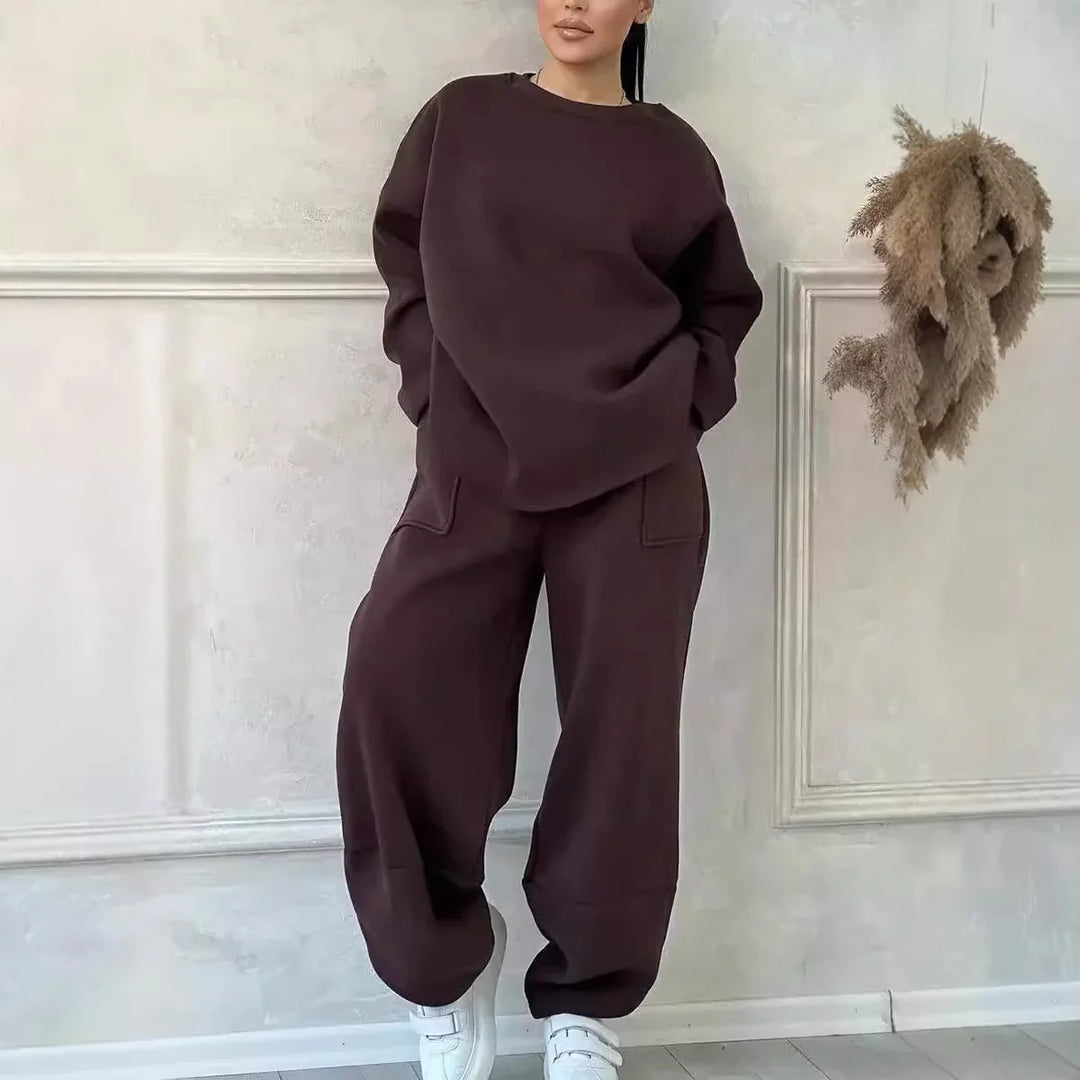 Woman wearing dark brown oversized sweatshirt and matching jogger pants with white sneakers indoors