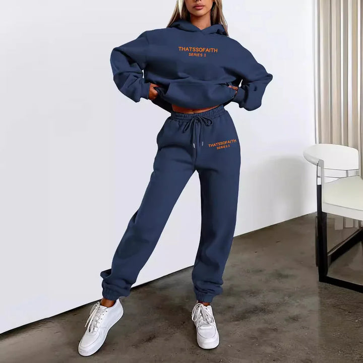 Woman wearing navy blue matching sweat set with orange THATSOFAITH Series 2 logo, white sneakers