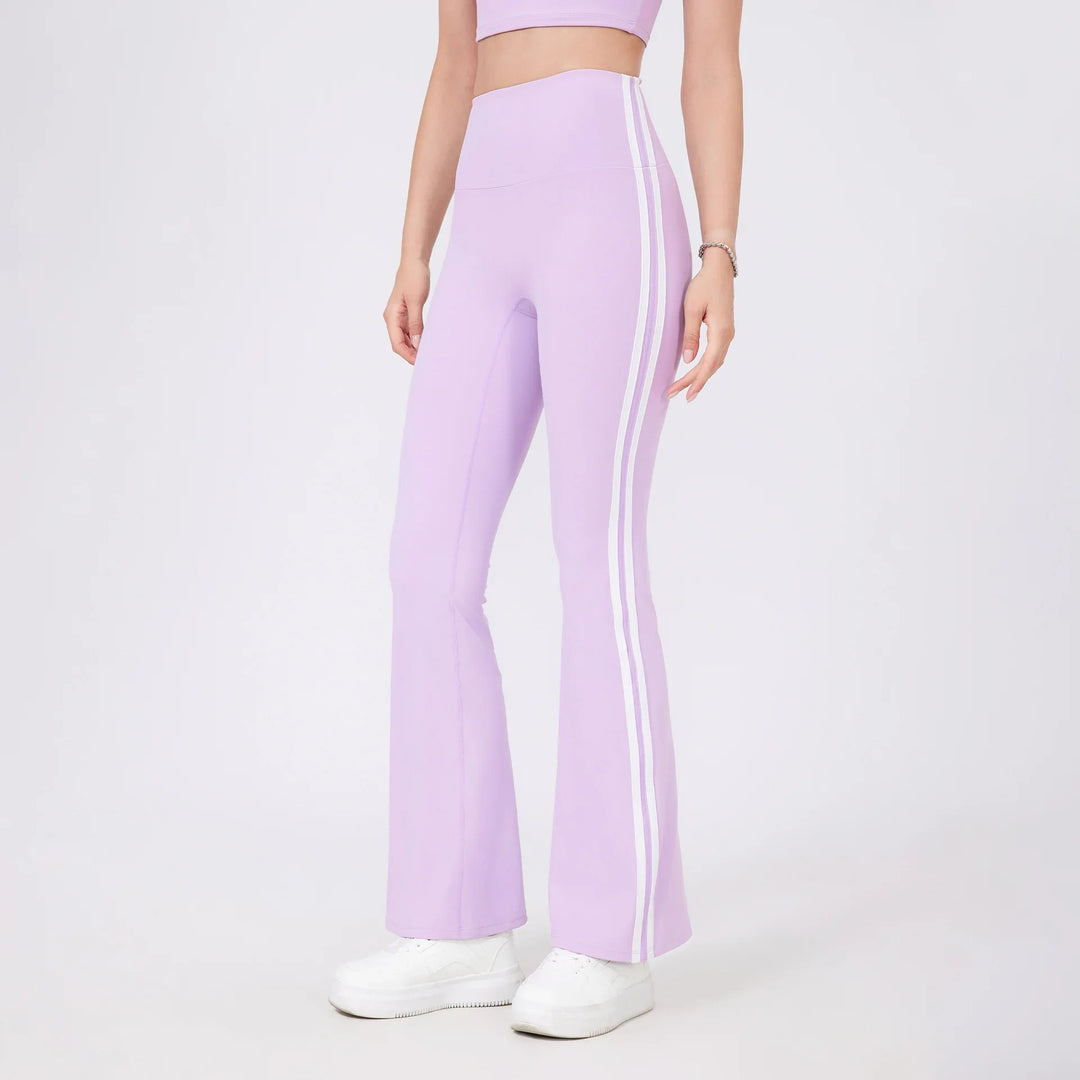 Woman wearing lilac high-waisted flared leggings with white side stripes and white sneakers