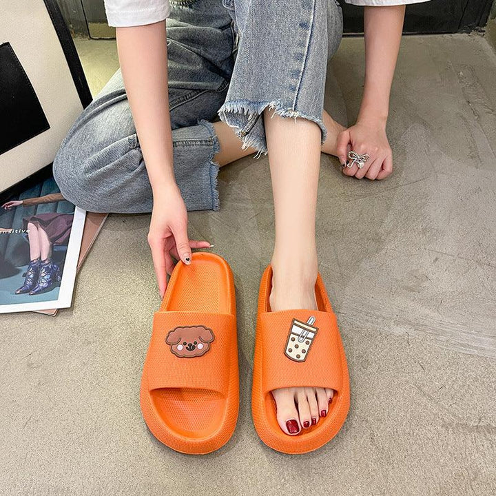Woman wearing orange slide sandals with dog and bubble tea designs, paired with cropped jeans