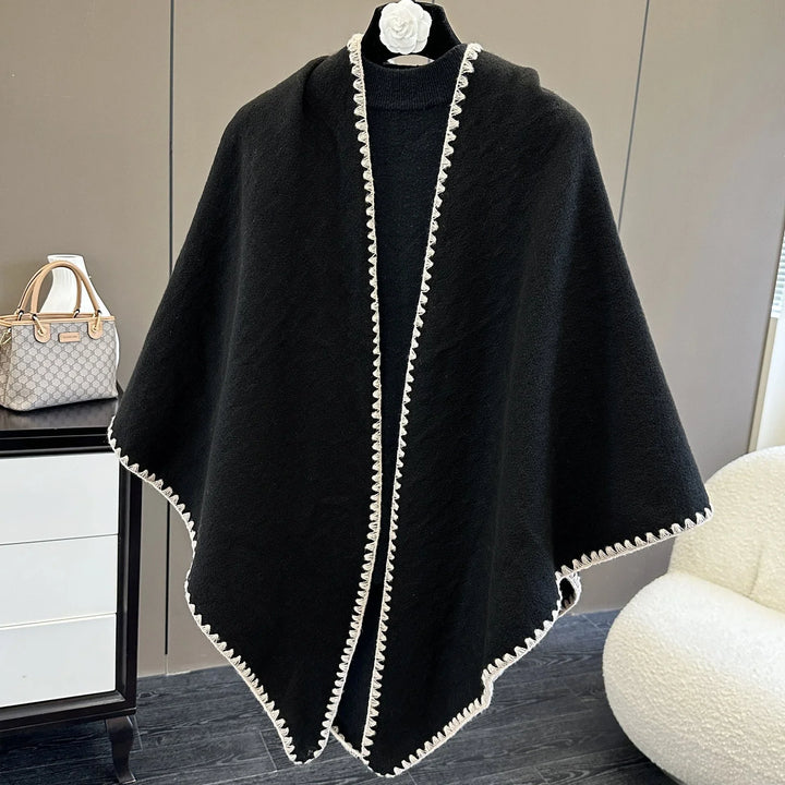 Black shawl with white scalloped trim displayed on mannequin in modern room setting