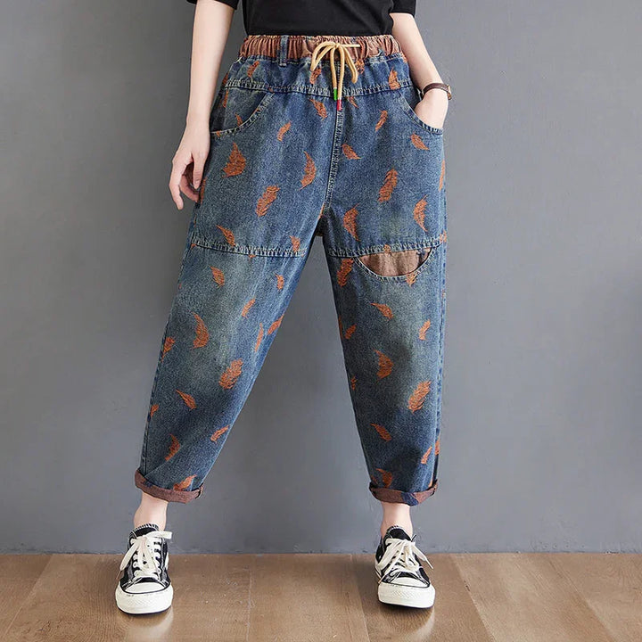 Casual loose-fit denim pants with orange feather prints, elastic waistband, and rolled cuffs