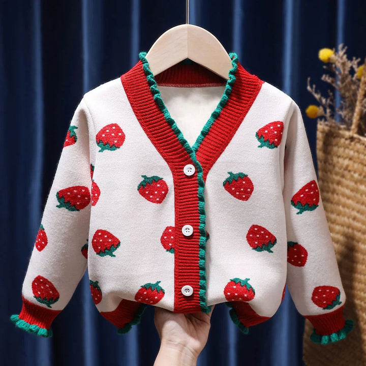 White knitted cardigan with red strawberries pattern, red and green ruffled trim, and white buttons