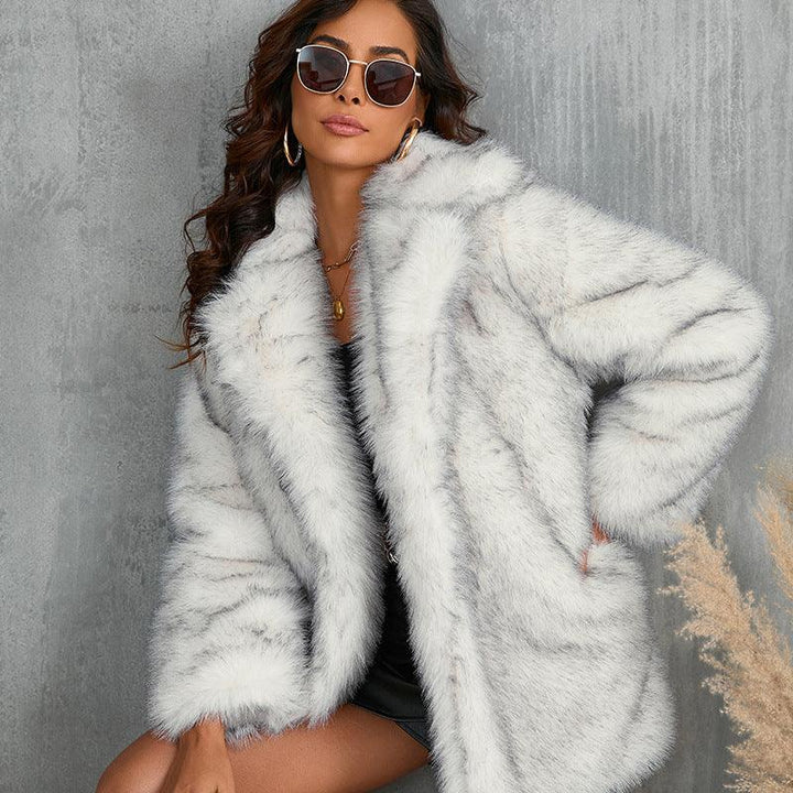 Woman wearing white faux fur coat and sunglasses against gray wall, posing fashionably