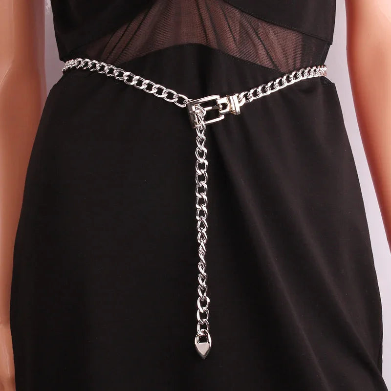 Silver chain belt with buckle detail worn over black dress featuring sheer mesh panel