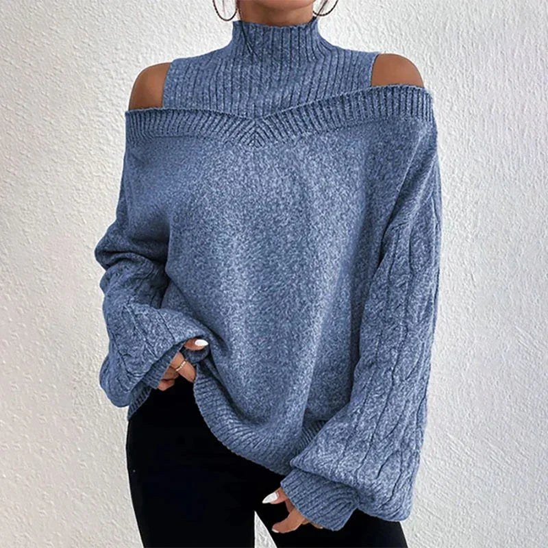 Woman wearing gray cold shoulder knitted sweater with high neck and cable knit sleeves