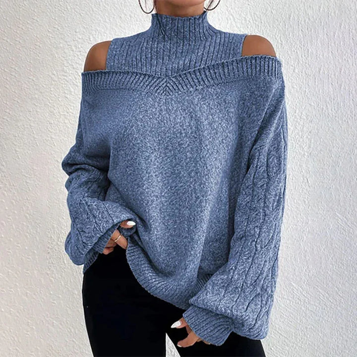 Woman wearing gray cold shoulder knitted sweater with high neck and cable knit sleeves