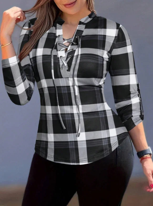 Woman wearing black and white plaid lace-up long sleeve shirt with rolled cuffs and black pants