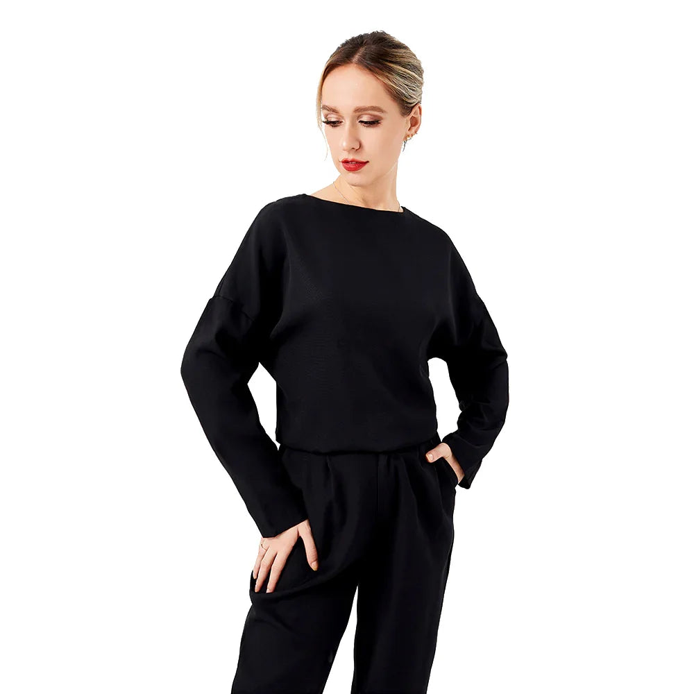 Woman in black long-sleeve top and pants posing against white background fashion apparel
