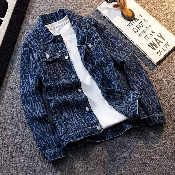 Blue denim jacket with white printed letters and a white T-shirt underneath on gray carpet