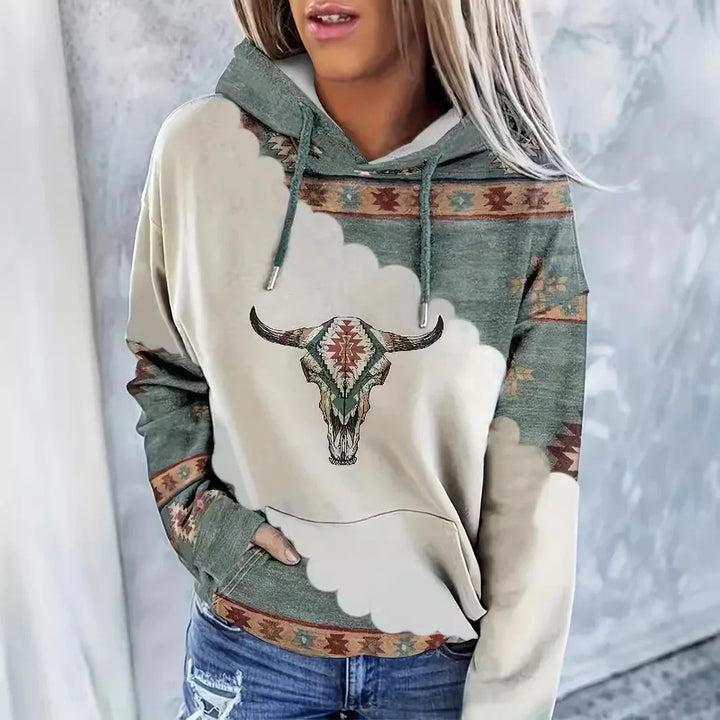 Woman wearing southwestern style hoodie with bull skull graphic and ethnic patterns, paired with ripped jeans