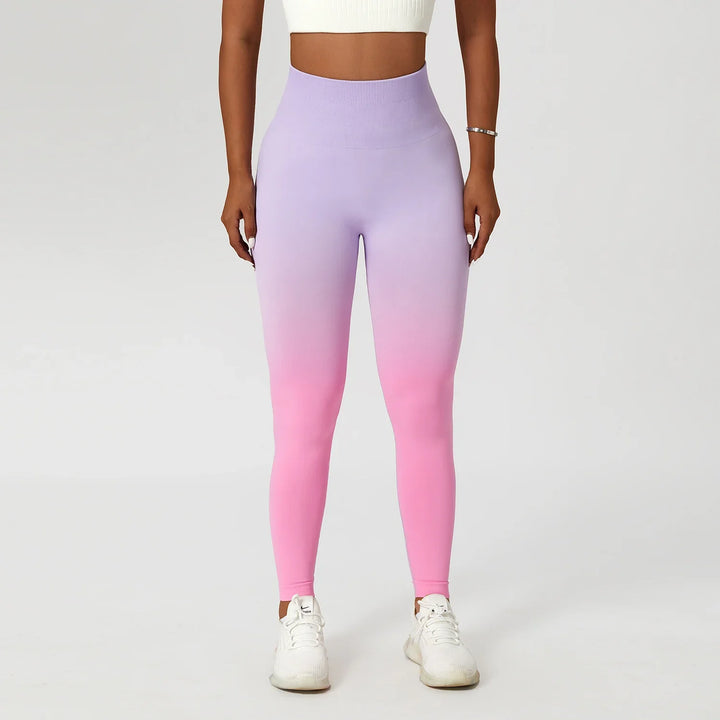 Woman wearing high-waisted ombre purple to pink leggings, white crop top, and sneakers