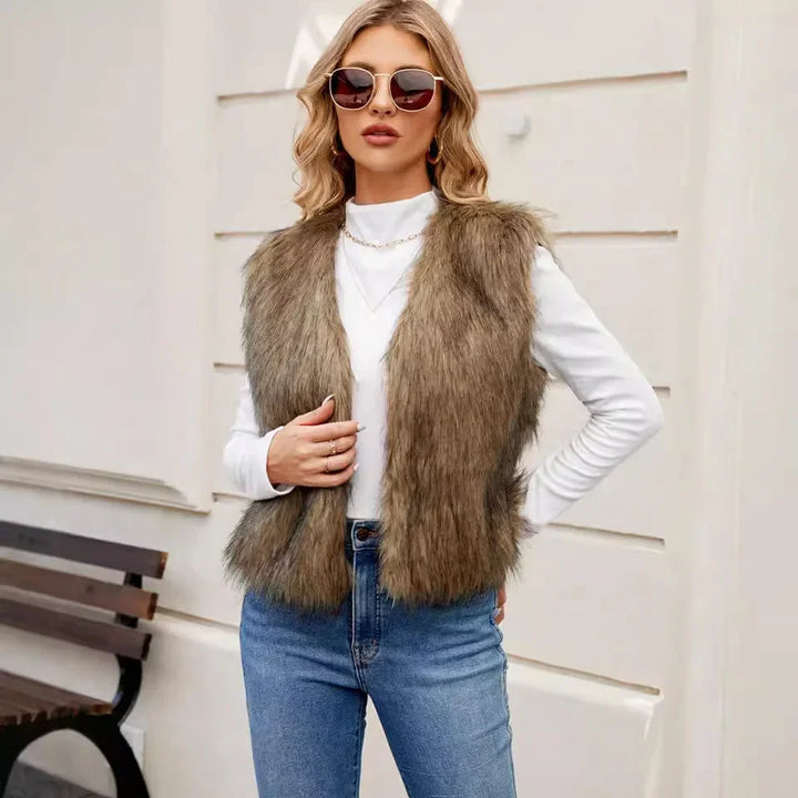 Fashionable woman wearing brown faux fur vest, white turtleneck, blue jeans, and sunglasses outdoors