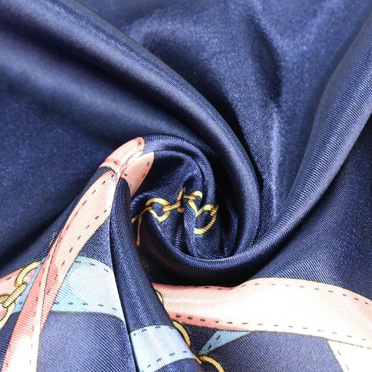 Close-up of smooth navy blue satin fabric with pink and gold chain pattern details