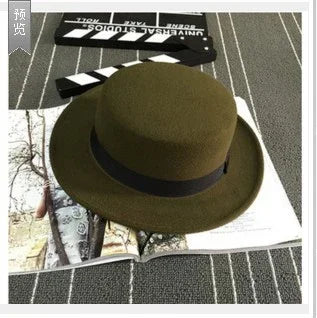 Olive green wool fedora hat with black band on patterned fabric background with film clapperboard