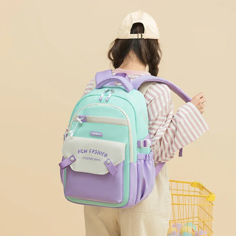 Young woman wearing mint green and lavender backpack with front pocket text 'NEW FASHION', beige cap, striped shirt