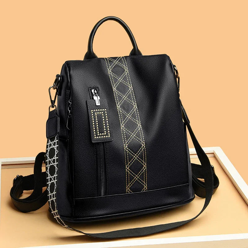 Black leather backpack with yellow diamond stitching and front zipper pocket on beige background