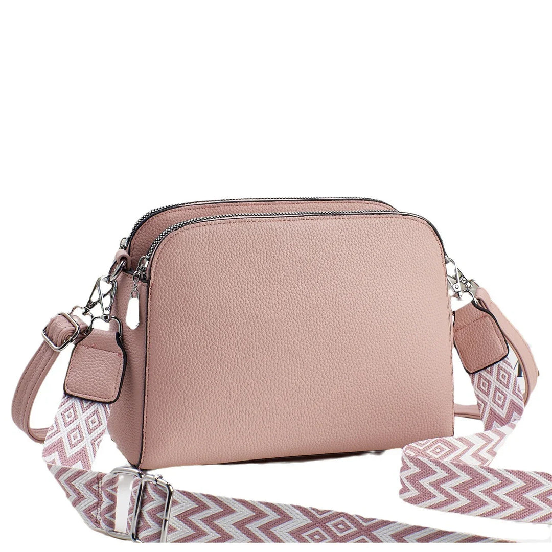 Pink double zipper crossbody bag with textured leather and adjustable patterned strap