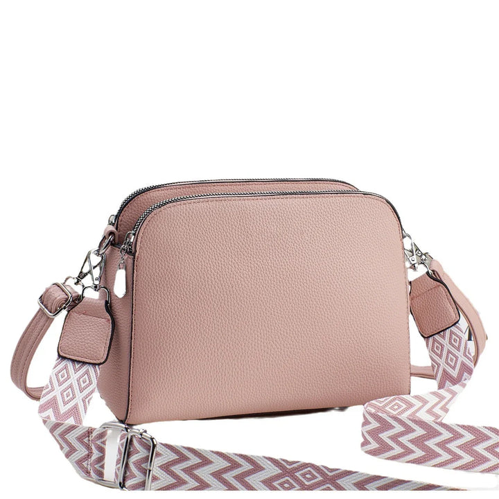 Pink double zipper crossbody bag with textured leather and adjustable patterned strap