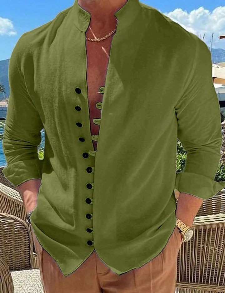 Man wearing olive green long-sleeve shirt with black buttons and rolled cuffs, outdoor patio background