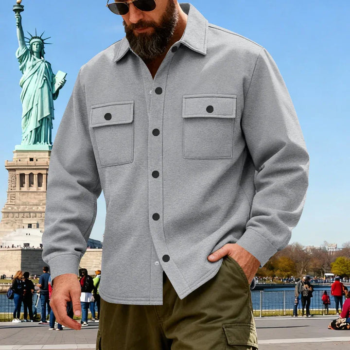 Man in gray button-up shirt and olive cargo pants near Statue of Liberty on sunny day