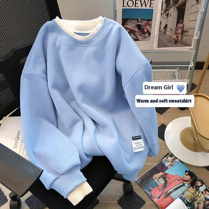 Light blue warm sweatshirt with white cuffs on office chair surrounded by fashion magazines and posters