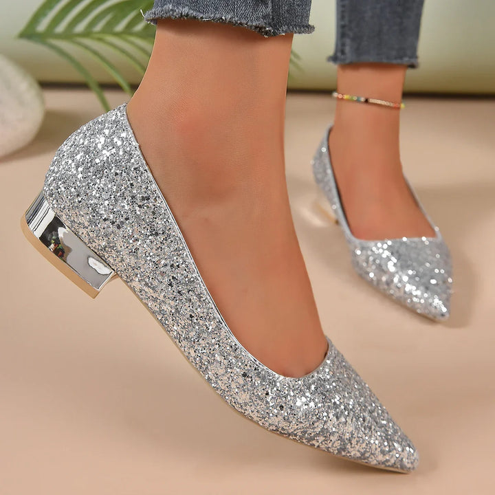 Woman wearing silver glitter pointed toe low heel shoes with ankle bracelet and frayed jeans