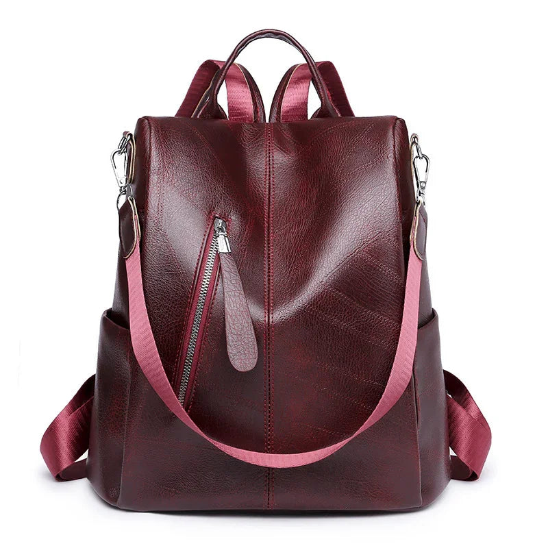 dark red leather backpack with pink shoulder strap, front zipper pocket, and side pockets